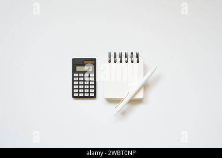 Black calculator, notepad, pen on white desk background. flat lay, top view Stock Photo