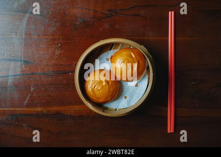 Steamed bun with egg yolk filing also known as Bakpao Telur Asin on wooden table Stock Photo
