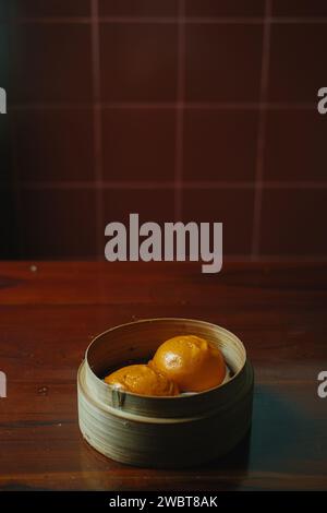 Steamed bun with egg yolk filing also known as Bakpao Telur Asin on wooden table Stock Photo