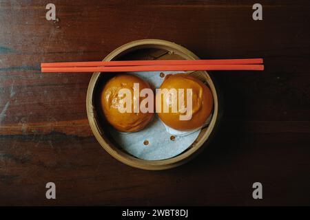 Steamed bun with egg yolk filing also known as Bakpao Telur Asin on wooden table Stock Photo