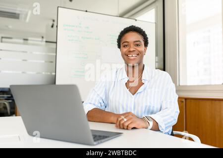 Headshot of friendly and positive African-American woman with short hair in smart casual wear, female office employee, manager, ceo, hr looking at the camera, smiling widely. Employee profile Stock Photo