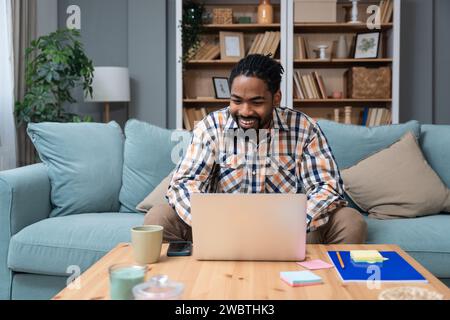 Focused young African American freelance businessman study online watching webinar podcast on laptop listening learning education course conference ca Stock Photo