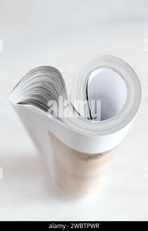 Rolled up magazine, newspaper, selective and shallow focus, white background,copy space Stock Photo