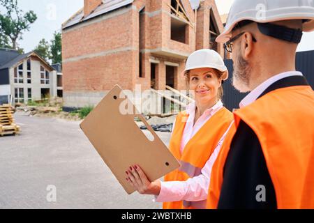 Pleased construction manager showing building documentation to foreman Stock Photo