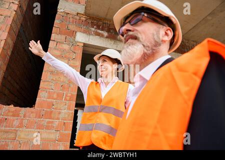 Site manager showing half-constructed building object to customer Stock Photo