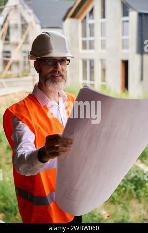 Construction foreman using blueprints on building site Stock Photo
