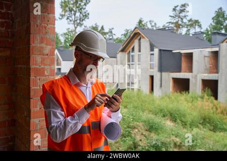 Focused construction worker using mobile phone on building site Stock Photo