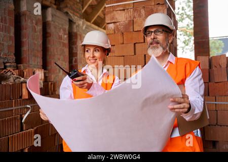 Construction specialists using blueprints during site inspection Stock Photo