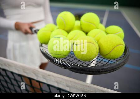 Unknown woman player holding lots tennis balls on racket Stock Photo