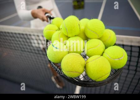 Unrecognizable woman player holding lots tennis balls on racket Stock Photo