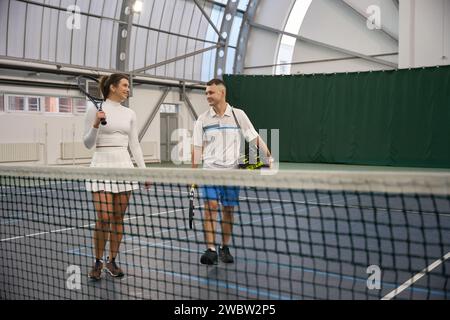 Woman with man instructor after playing tennis game at indoor court Stock Photo