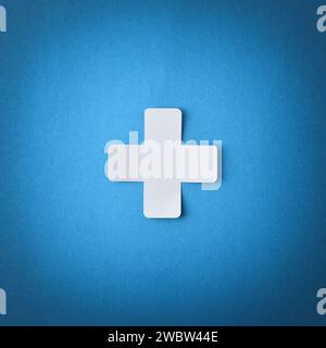 Conceptual symbol with cross shaped paper cutout isolated in the center on blue background. Square composition Stock Photo