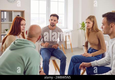 Adult men and women are discussing their problems during a group therapy session Stock Photo