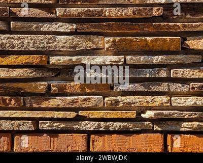 The masonry wall are made of gray wild flat stone and bricks. Side natural sunlight. Copy space. Close-up. Stock Photo