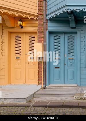 A pair of brightly colored doors, one in a deep turquoise blue and the other in a sunny lemon yellow, stand side-by-side on a narrow cobblestone street in Kuzguncuk neighborhood, Istanbul, Turkey Stock Photo