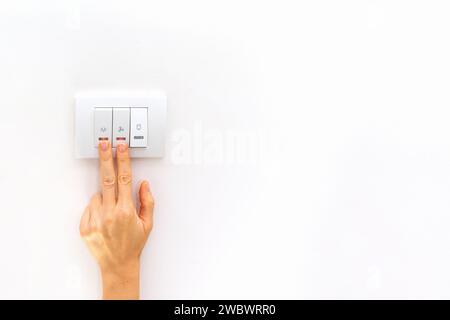 Two females fingers on electric light switch on white background with copy space. Stock Photo
