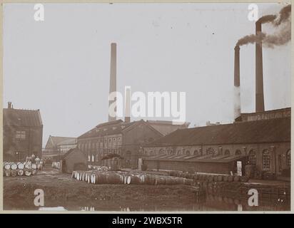 Exterior of factory buildings and smoking chimneys, with wooden barrels in the foreground, anonymous, c. 1900 - c. 1910 photograph Part of Family Album with photos of Wijnhandel Kraaij & Co. Bordeaux-Amsterdam.  photographic support  factory-building. smoke-stack. wooden container: barrel, cask (+ wood and other phytogenic material) Stock Photo