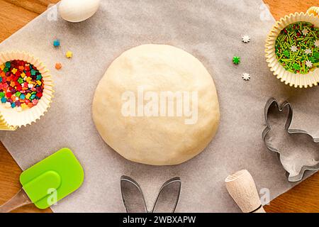 Dough for making Easter cookies, cookie cutters, sugar sprinkles. Festive Easter background for baking. Stock Photo