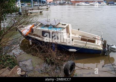 Cookham, UK. 12th January, 2024. A boat looks like it has seen better days after flooding in Cookham. The village of Cookham in Berkshire is slowly beginning to dry out after the River Thames burst its banks last weekend. The river levels are finally dropping. Now the expensive clean up will begin by residents and the Royal Borough of Windsor & Maidenhead. Credit: Maureen McLean/Alamy Stock Photo