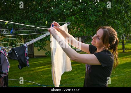 smiling woman hangs clean clothes on a hanger. Stock Photo