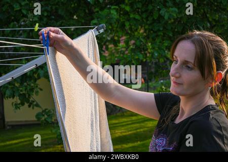 smiling woman hangs clean clothes on a hanger. Stock Photo