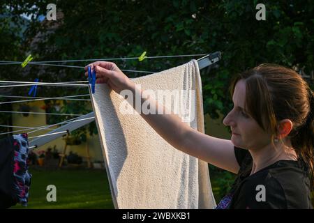 smiling woman hangs clean clothes on a hanger. Stock Photo