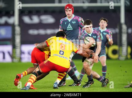 Ospreys' Morgan Morse (centre) is tackled by USA Perpignan's Sootala Faasoo (8) during the EPCR Challenge Cup match at the Swansea.com Stadium, Swansea. Picture date: Friday January 12, 2024. Stock Photo