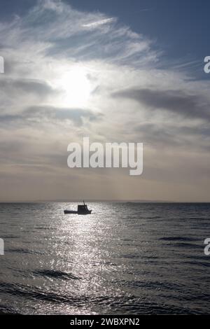 Small boat captured in the sunlight off the coast of Thorpe Bay, near Southend-on-Sea, Essex, England, United Kingdom Stock Photo