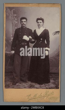 Double portrait of a soldier with his wife, L.M. de Rijk, c. 1890 - c. 1900 photograph. cabinet photograph  Utrecht photographic support. cardboard  private soldier. hacking and thrusting weapons Stock Photo