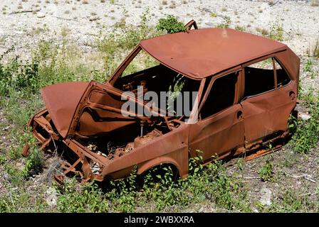 small rusty wrecked car next to the road, somewhere in France Stock Photo