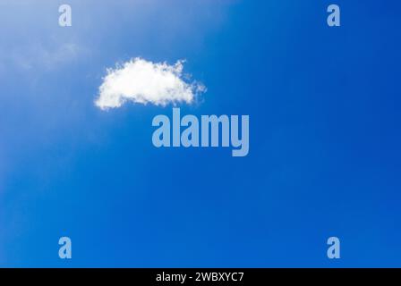 one single small fluffy white fair weather cloud (cumulus humilis) in blue sky Stock Photo