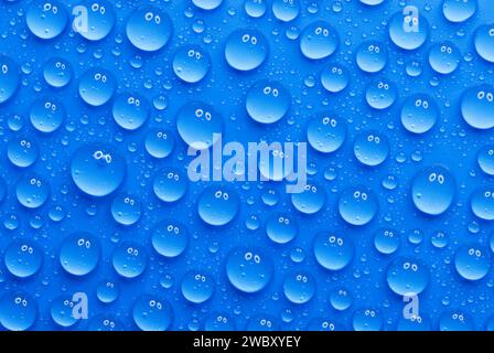 closeup, macro of many water drops, droplets, on a blue surface, background, a pair of eyes that are reflected in every drop Stock Photo