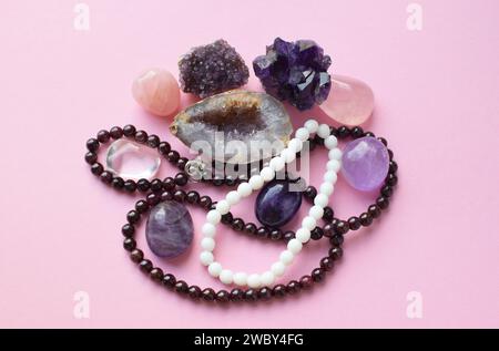 Garnet beads and amethyst, rose quartz and rock crystal crystals on a pink background. Stock Photo