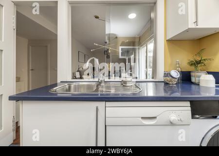 Kitchen with stainless steel sink, serving hatch and blue countertop Stock Photo