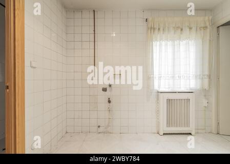 Office of an empty kitchen with old white tiles and a window with curtains Stock Photo