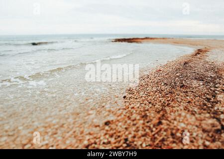 Blue turquoise ocean sea waves. Mediterranean coast shoreline landscape. Stone beach with pebbles in gloomy day. Volcanic black sand, cold water. Stock Photo