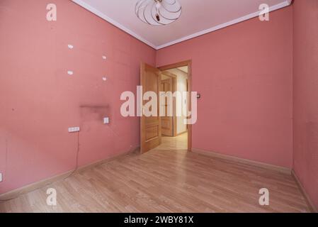 An empty room with terracotta painted walls, plaster moldings on the ceiling and a circular ceiling lamp Stock Photo