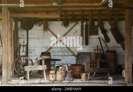 Collection of planers and retro wood saws hang on a wooden wall near an old house. Carpenters plane and other things on the wall Stock Photo