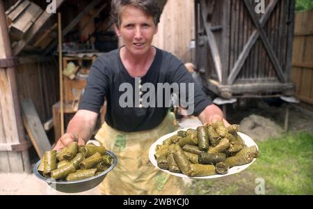 Vrancea County, Romania, approx. 1999. Local woman with plates of grape leave rolls for an event. Stock Photo