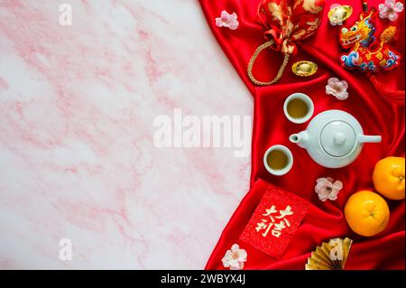 Tea set on red cloth background with red envelope packets or ang bao(word mean auspice), red bag, ingots(word mean wealth), hanging pendant dragon and Stock Photo