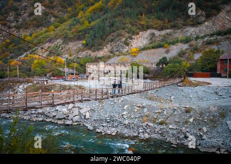 Two men crossing a river on a high suspension bridge while walking Stock Photo