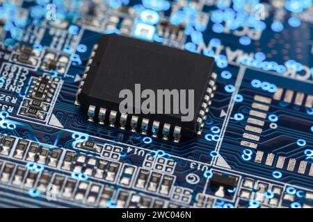 A microprocessor on a printed circuit board surrounded by auxiliary elements, backlit through the board. Macrofto in dark colors Stock Photo