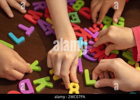 many kids hands holding colorful letters to read, top view Stock Photo