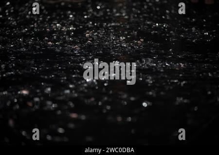 On a black background there are silver bokeh spots from shiny confetti. Stock Photo