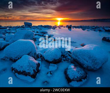 Winter sunset with snowy boulders and icy coastline at Teibern in Larkollen by the Oslofjord, Østfold, Norway, Scandinavia Stock Photo