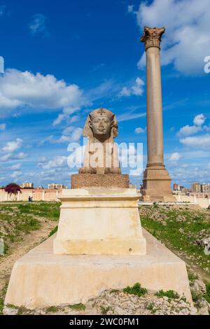 Sphinx and giant ancient Pompey's pillar on territory of Serapeum of Alexandria in Egypt Stock Photo