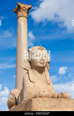 Sphinx and giant ancient Pompey's pillar on territory of Serapeum of Alexandria in Egypt Stock Photo