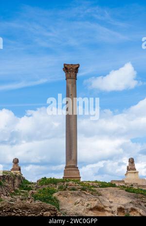 Two sphinxes and giant ancient Pompey's pillar on territory of Serapeum of Alexandria in Egypt Stock Photo