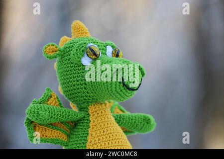 Knitted green dragon on blurred background, greeting card. Symbol of Chinese New Year 2024 Stock Photo