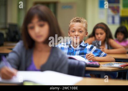 Students, classroom and writing for learning, elementary school and diverse children workbook. Portrait, study and childhood development for education Stock Photo